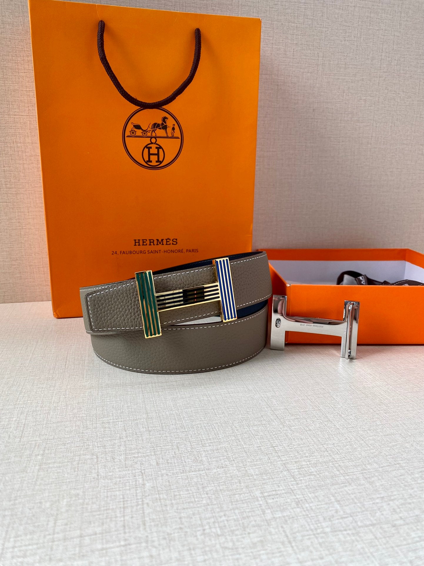 Hermes belt gray leather with striped buckle and gold buckle hardware on display