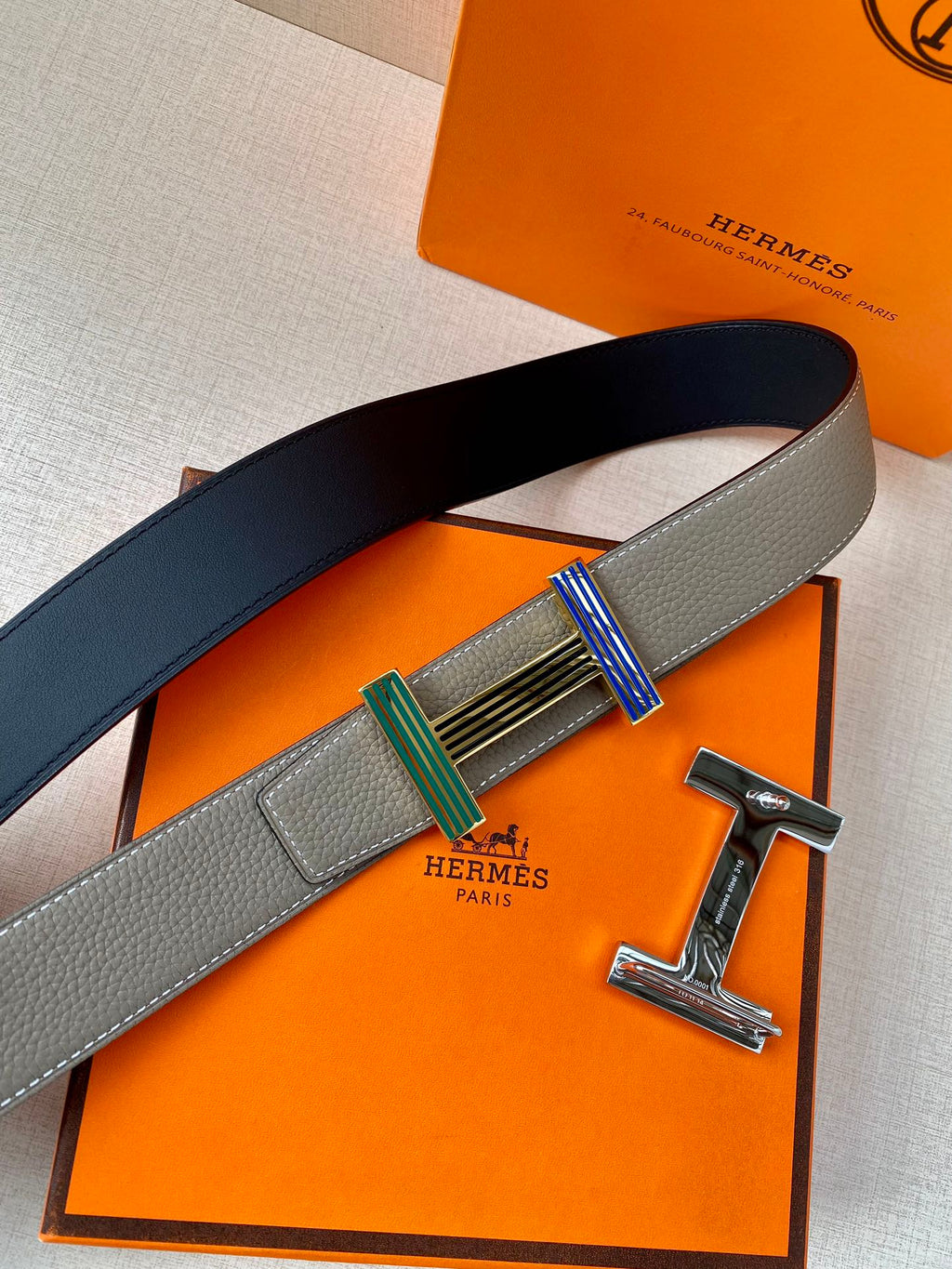 Hermes belt with gray and dark blue sides and striped buckle with gold frame