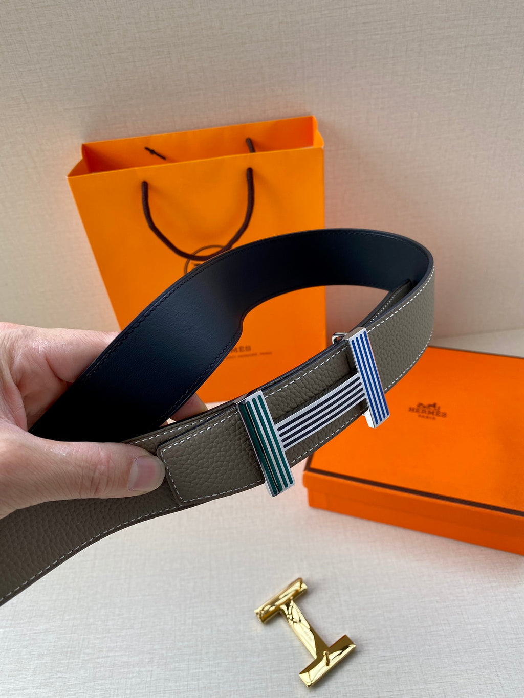 Hermes belt gray leather with navy strap, striped buckle center, and gold logo hardware