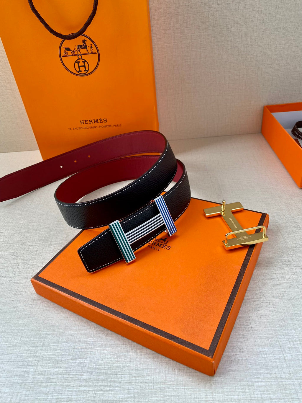 Hermes belt with dark blue leather strap, burgundy lining, and striped buckle