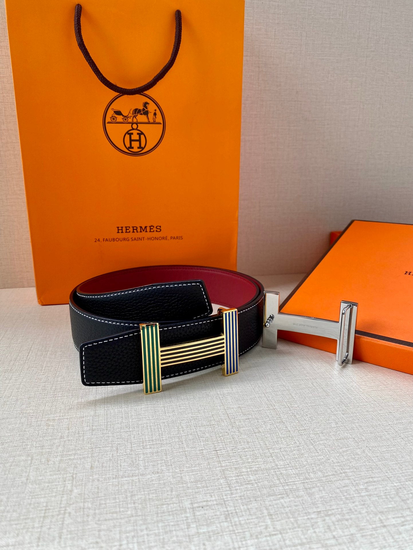 Hermes belt with dark blue leather strap, burgundy underside, and striped buckle