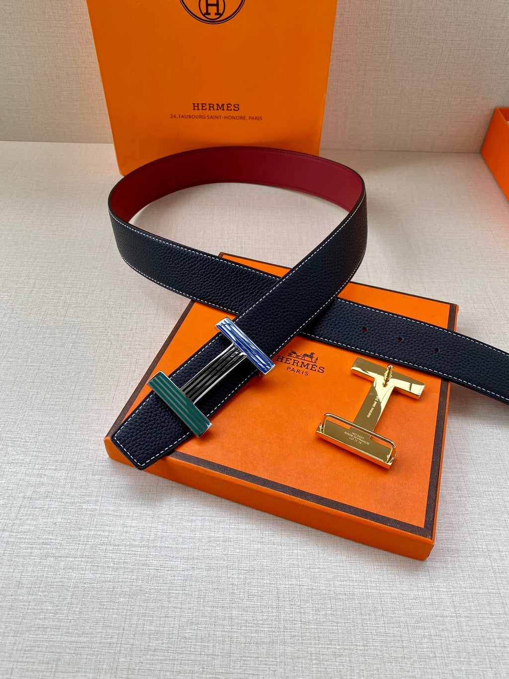 Hermes belt with dark blue leather strap and multicolor striped buckle on display