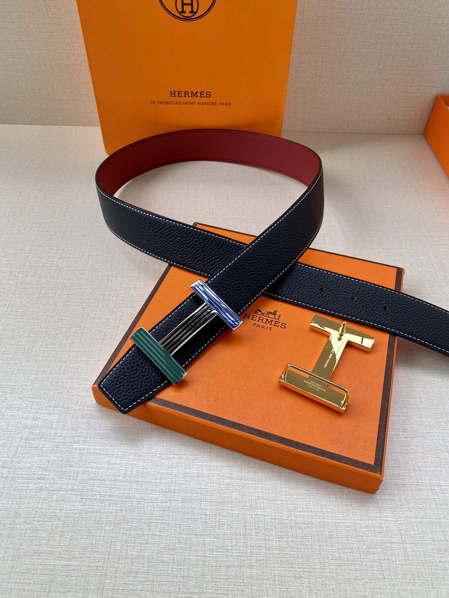 Hermes belt with dark blue leather strap and multicolor striped buckle on display