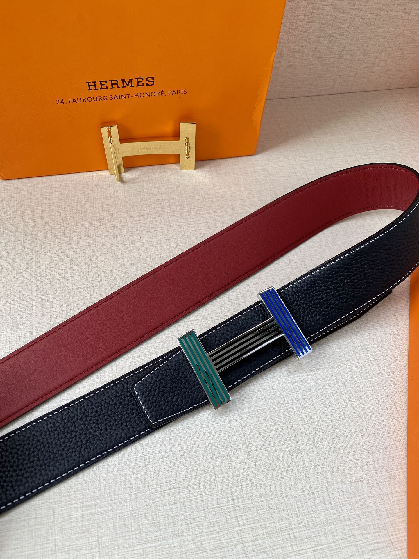 Hermes belt detail with dark blue strap, burgundy lining, and striped buckle