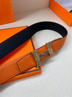 Orange leather belt with navy strap and gold-tone buckle centered on the front