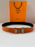 Orange leather belt with navy interior and gold-tone buckle, laid flat