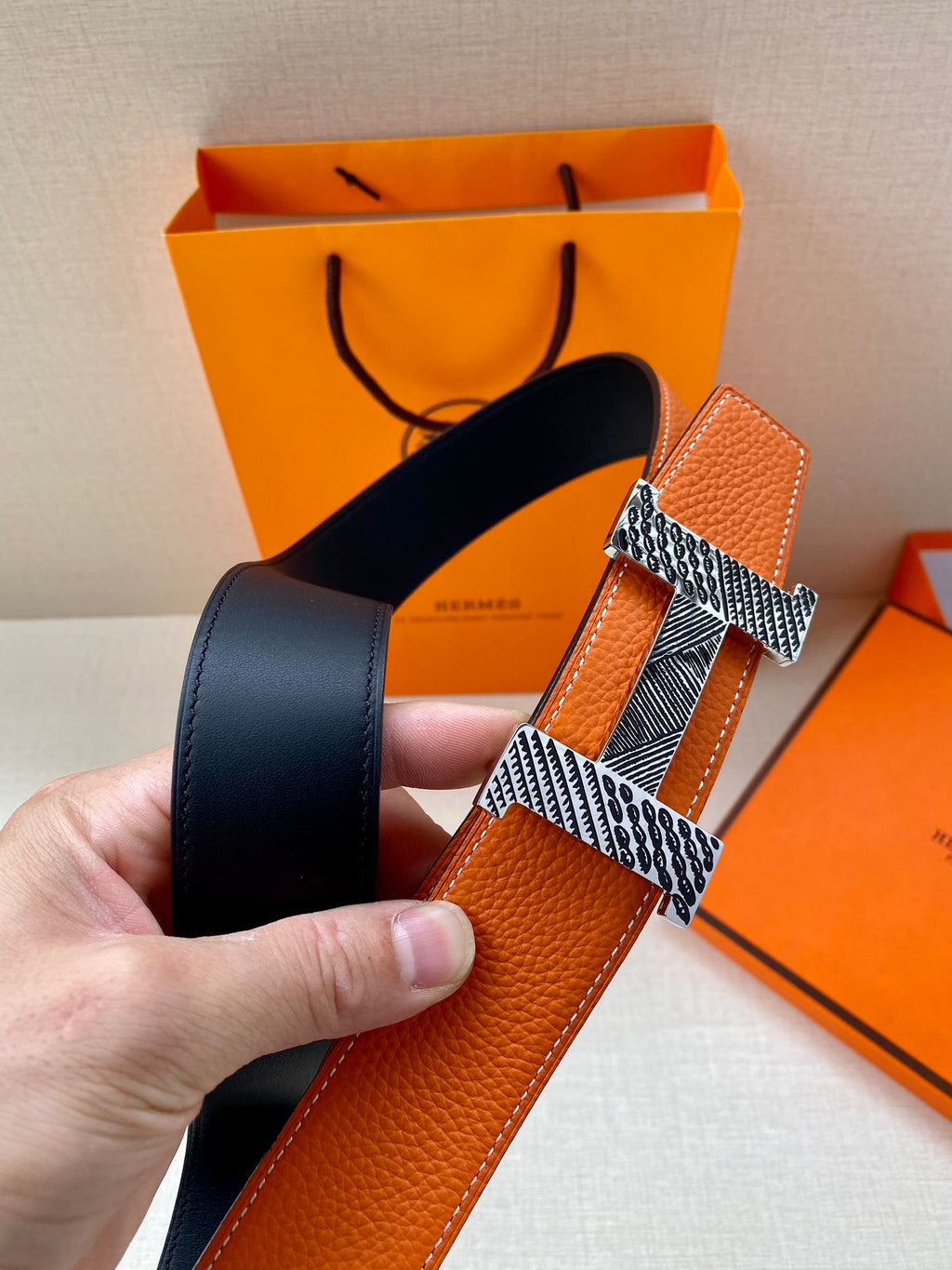 Orange leather Hermes belt with gold-tone buckle and dark navy strap backing