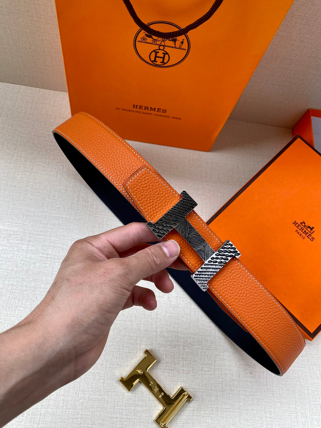 Hermes belt in orange textured leather with gold-tone buckle bar and dark underside