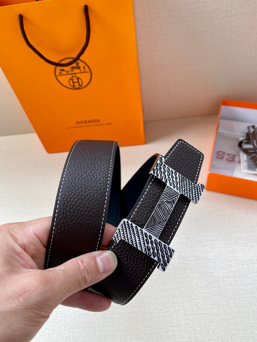 Hermes belt close-up, black leather strap with silver patterned buckle center