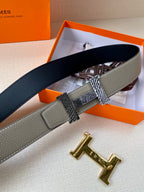 Hermes belt viewed side-on, navy strap with gray section and gold-toned H buckle