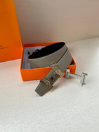Hermes belt with gray leather band and dark underside, gold H buckle on stand
