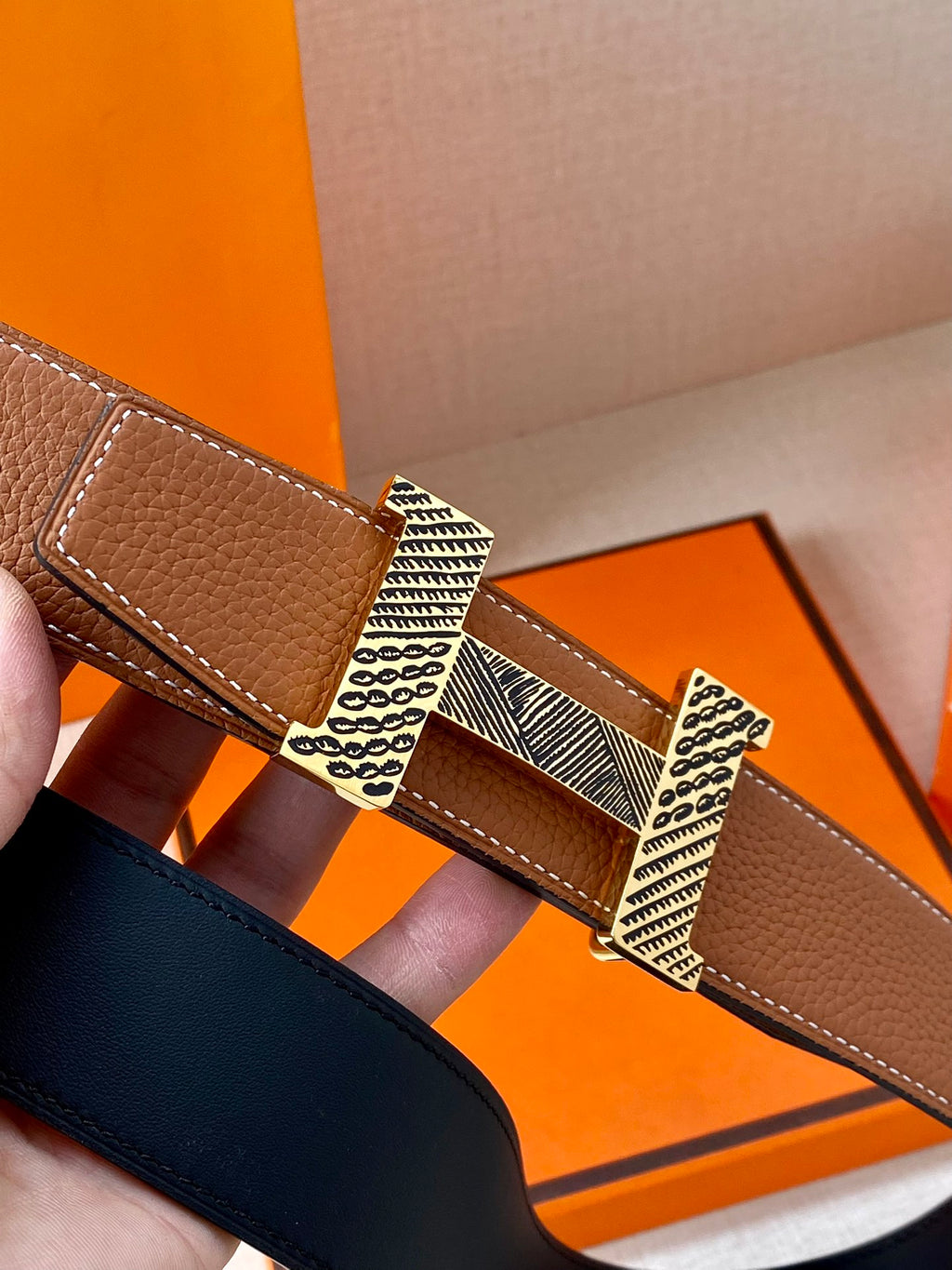 Hermes leather belt buckle close-up on brown strap with textured metal insert