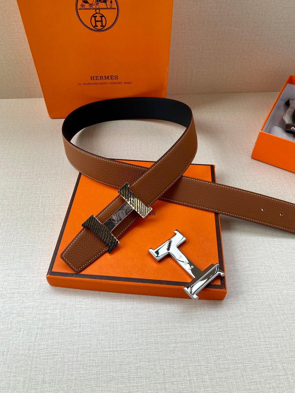 Hermes leather belt with brown strap and silver-tone buckle lying on box