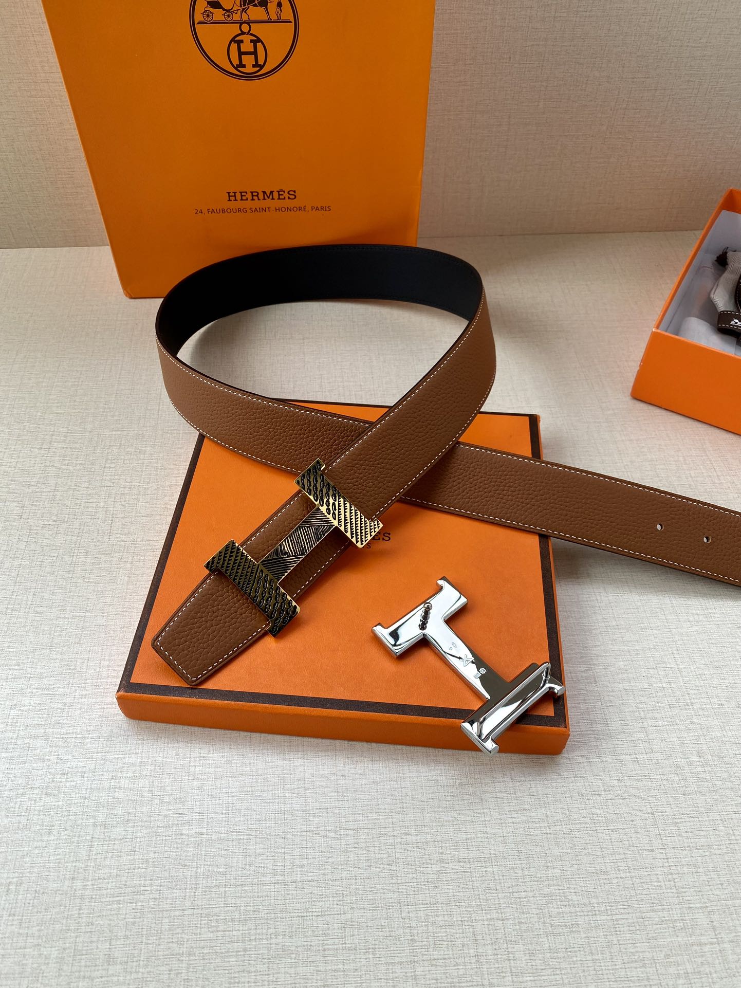 Hermes leather belt with brown strap and silver-tone buckle lying on box