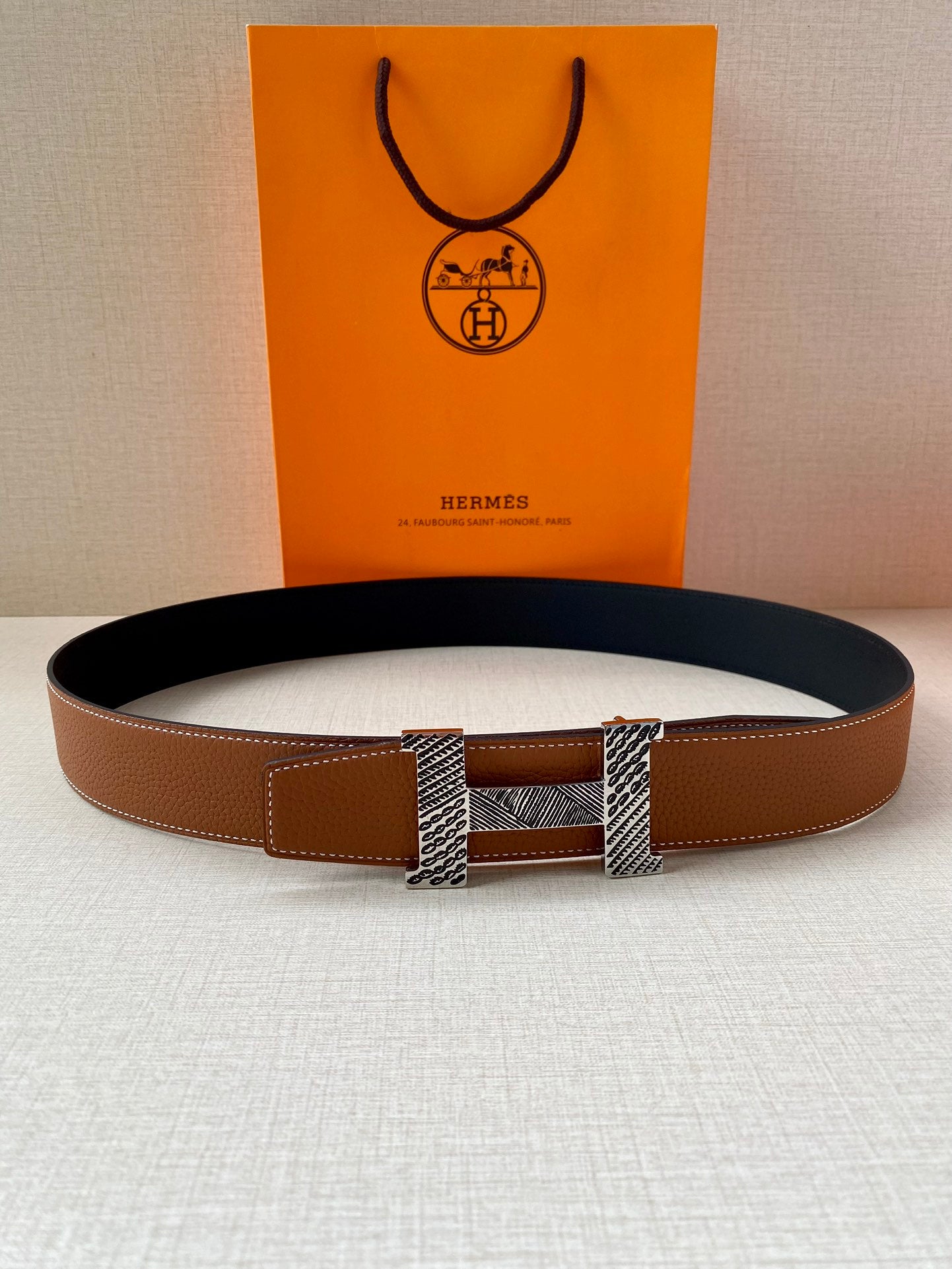 Hermes leather belt with brown strap and silver-tone buckle, laid flat