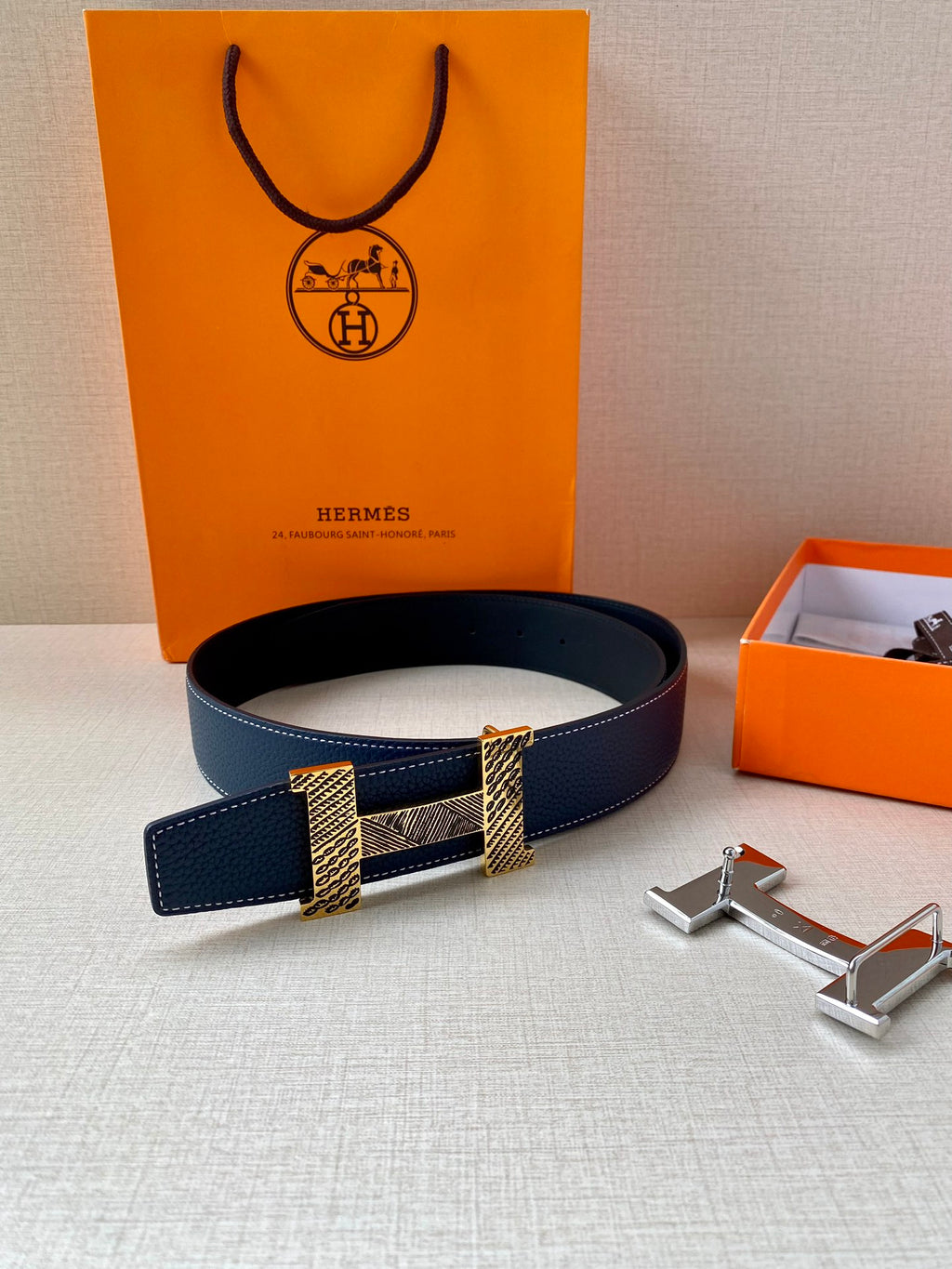 Navy blue leather belt with gold-tone buckle plates and silver prong hardware