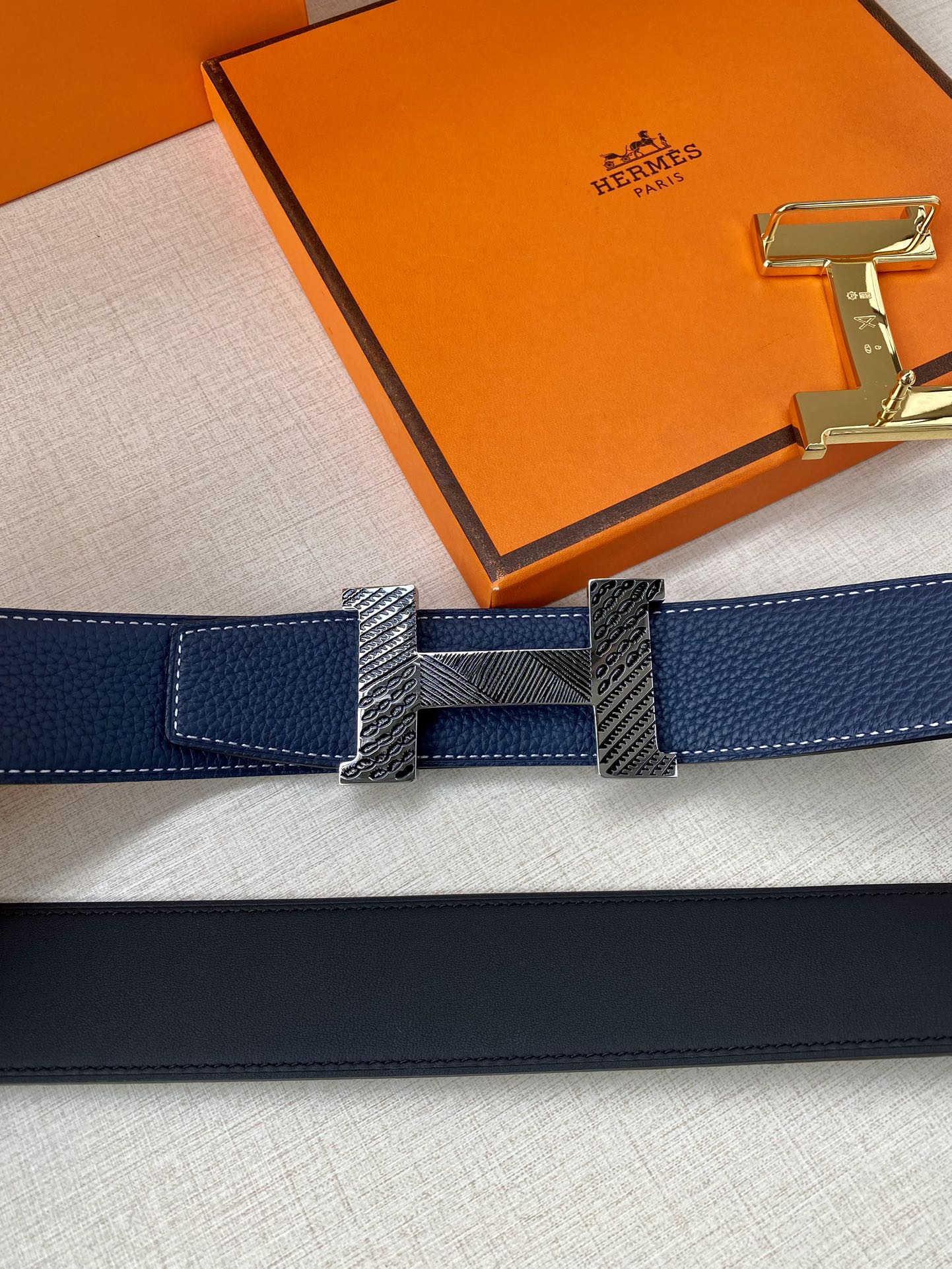 Blue leather belt with gold-tone buckle plate and interlocking textured center