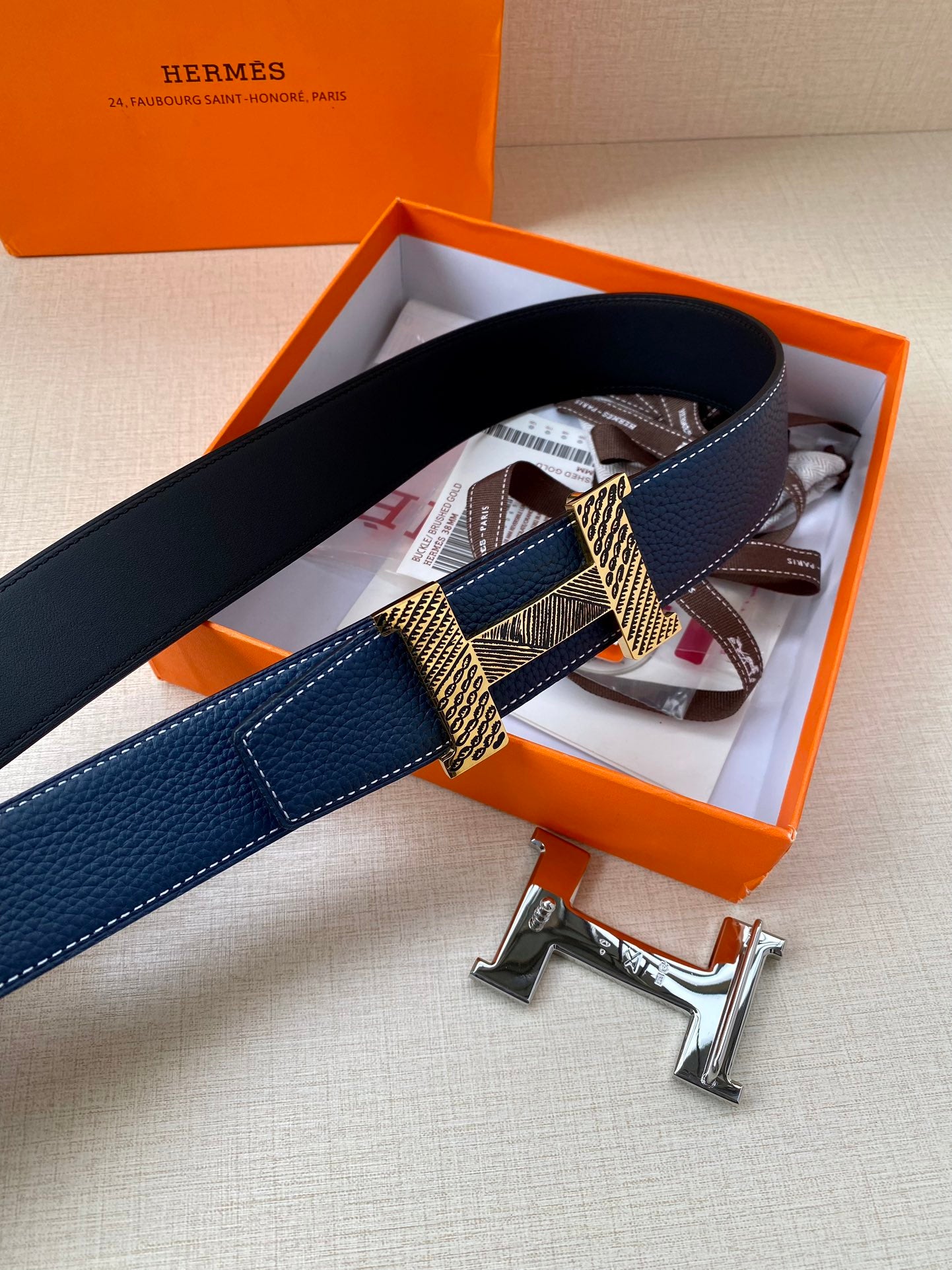 Blue leather belt in packaging, gold-tone buckle plates and textured center band