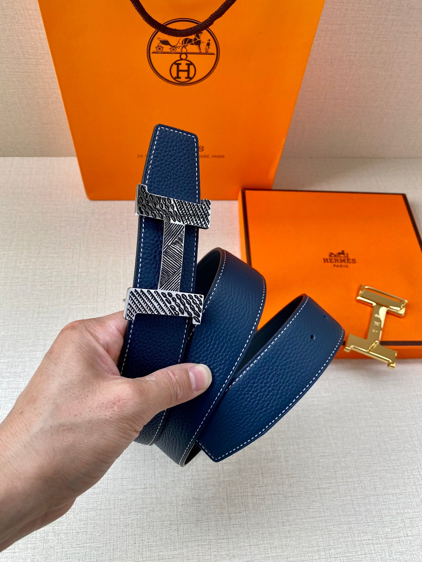 Blue leather belt with textured gold-tone buckle plates and matching strap end loop