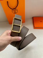 Taupe leather belt with gold-tone double square buckle held in hand