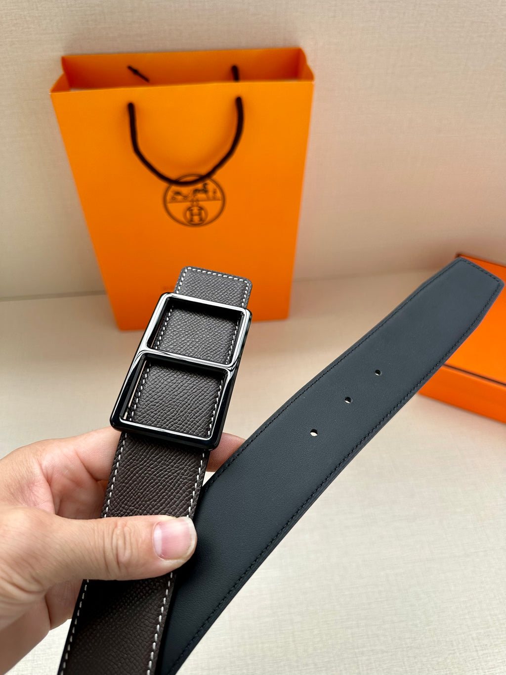 Leather belt with smooth dark strap and silver-tone buckle, belt holes visible