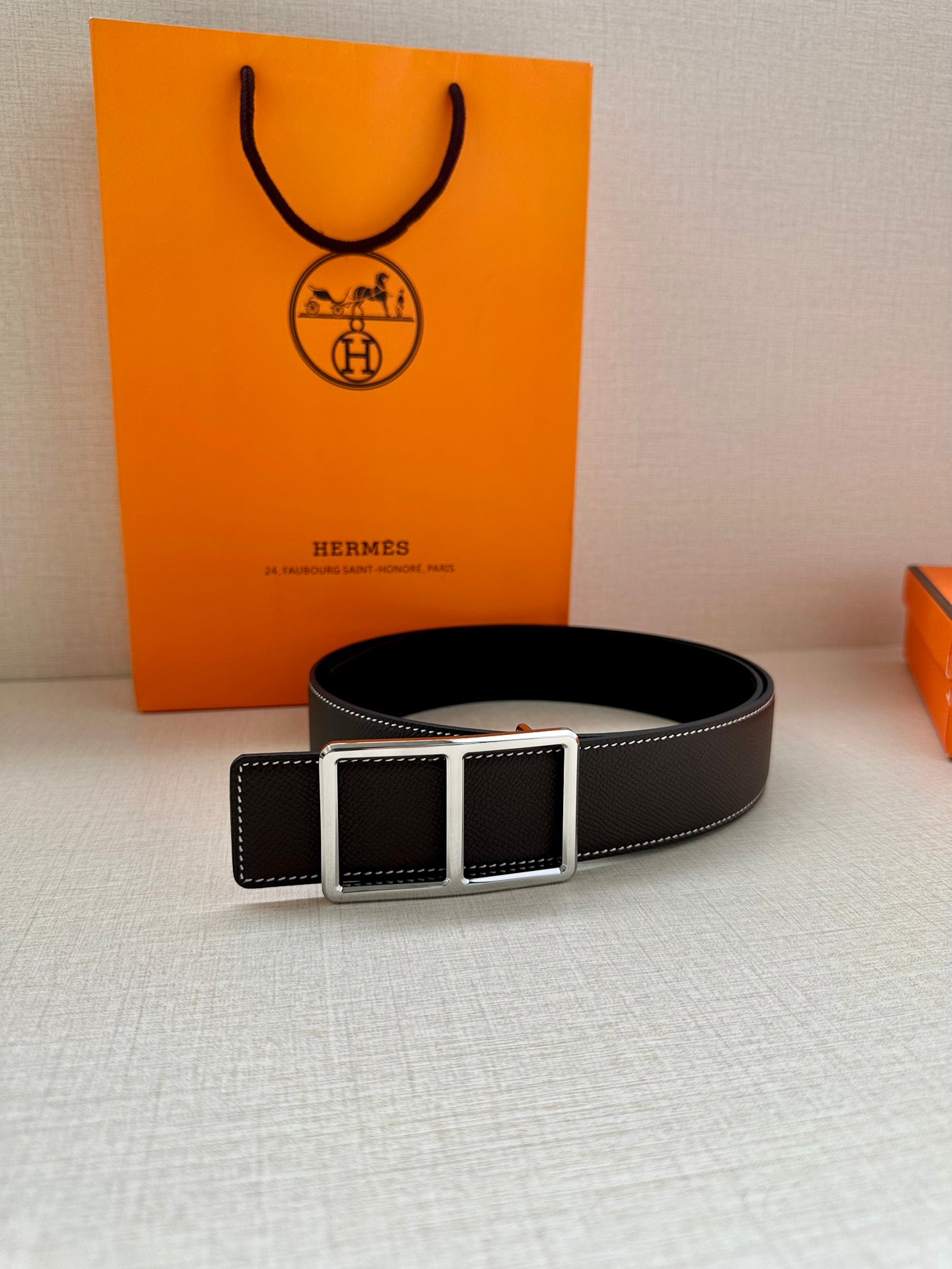 Leather belt with smooth dark strap and rectangular buckle, laid flat