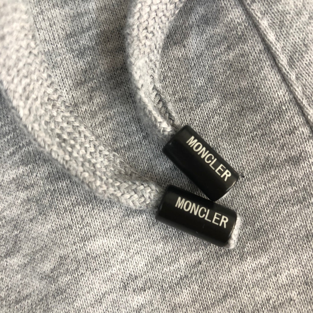 Moncler-branded drawstring cord ends on heather gray shorts waistband.