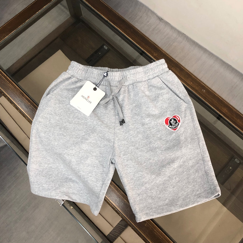 Grey drawstring shorts with Moncler heart logo patch, elastic waistband.