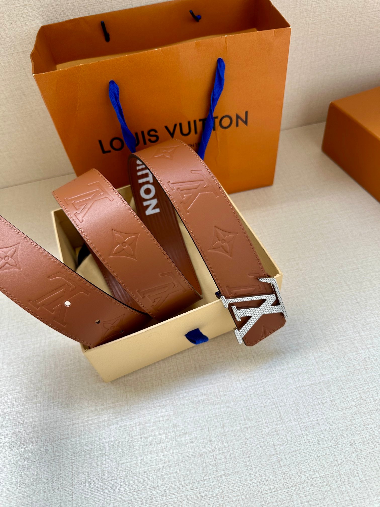 Louis Vuitton belt laid out with brown leather strap and large LV buckle