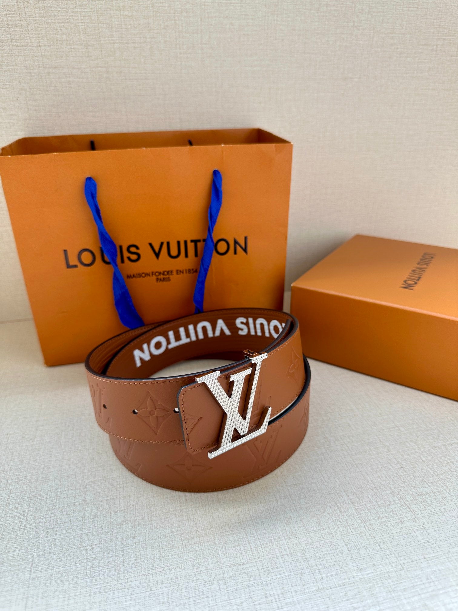 Louis Vuitton belt on white cloth with brown strap and silver-tone LV buckle