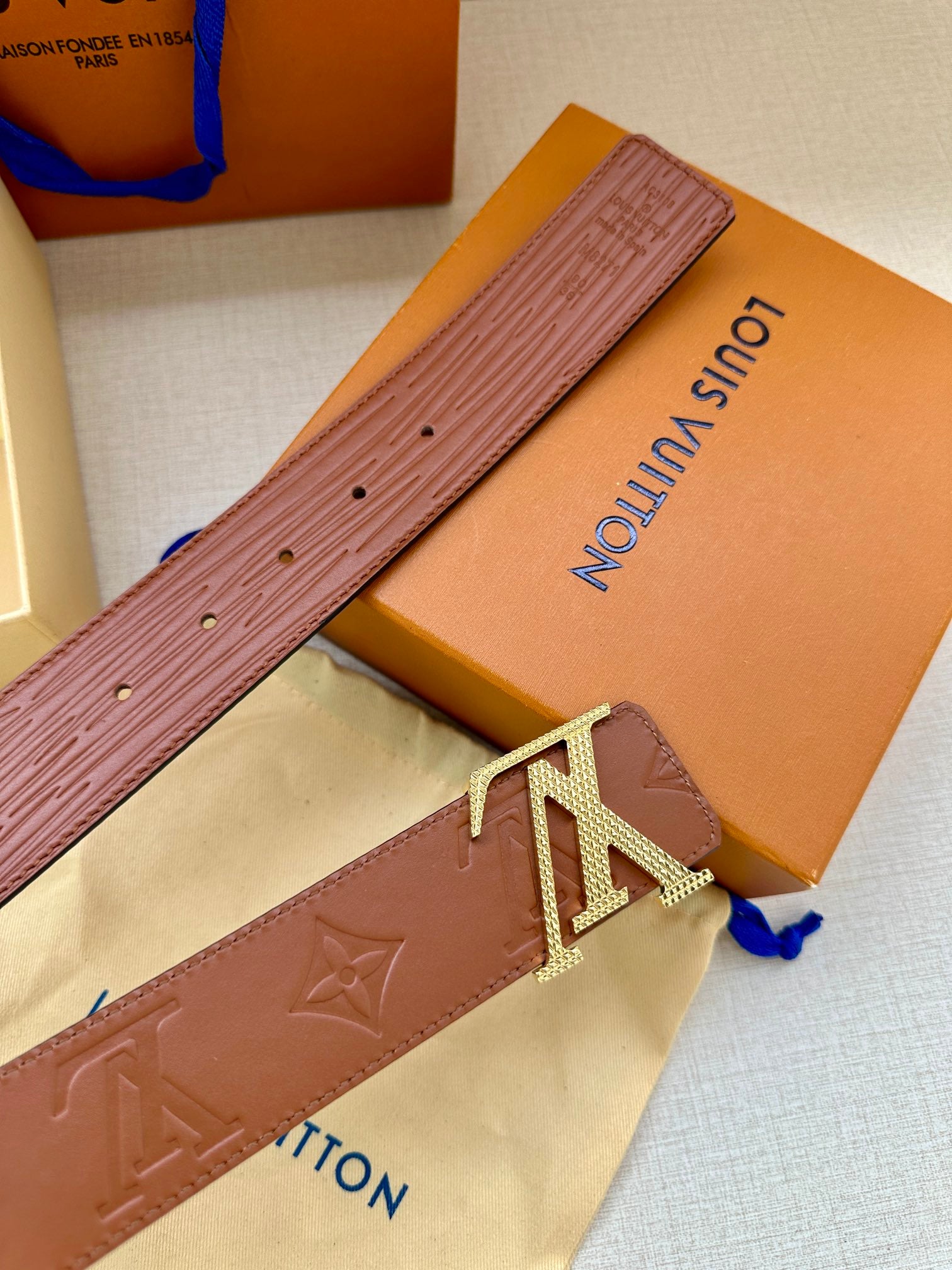 Louis Vuitton belt strap close-up in brown with embossed texture and LV buckle