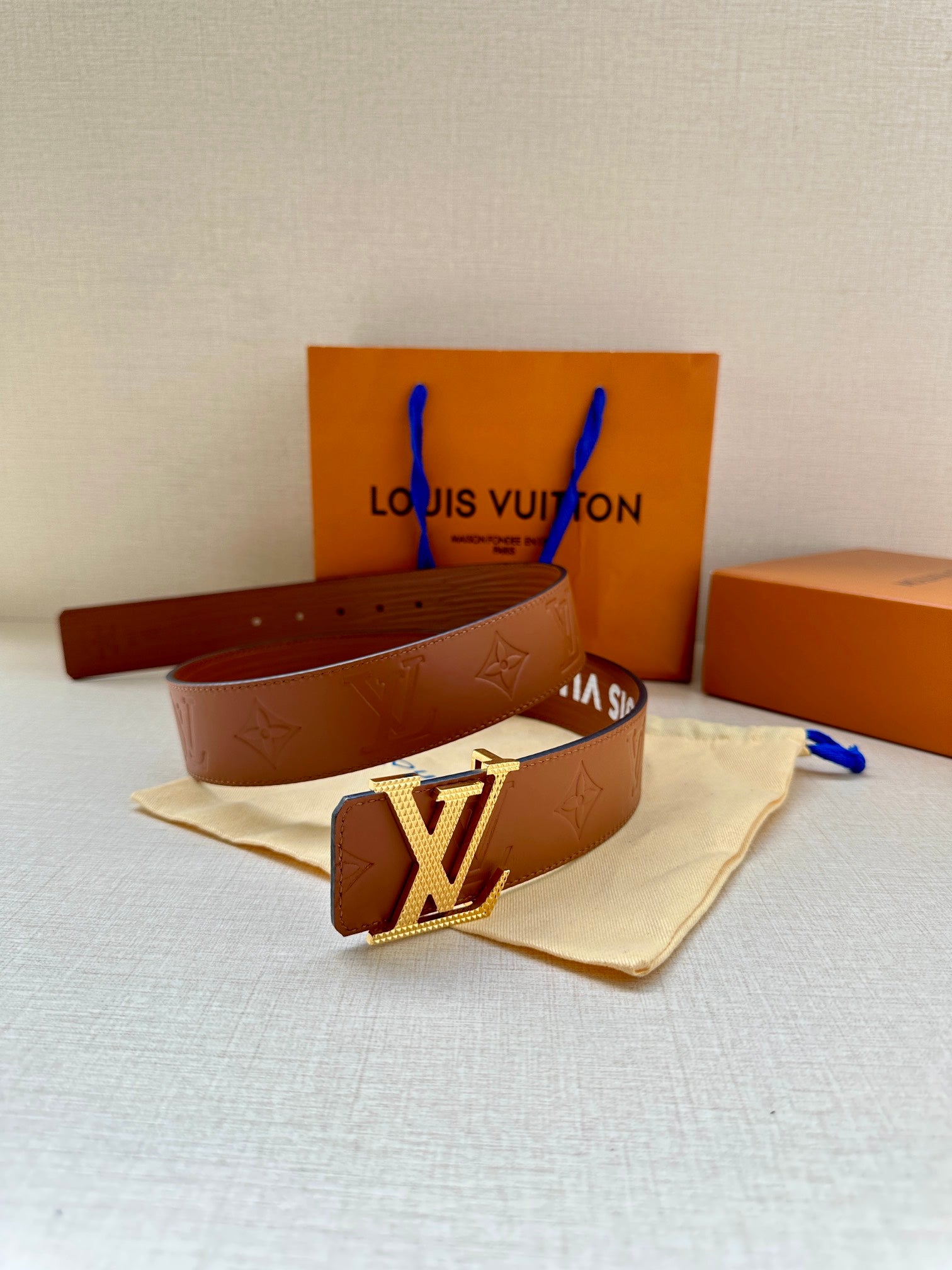 Louis Vuitton belt with brown strap, gold-tone LV buckle, and embossed pattern