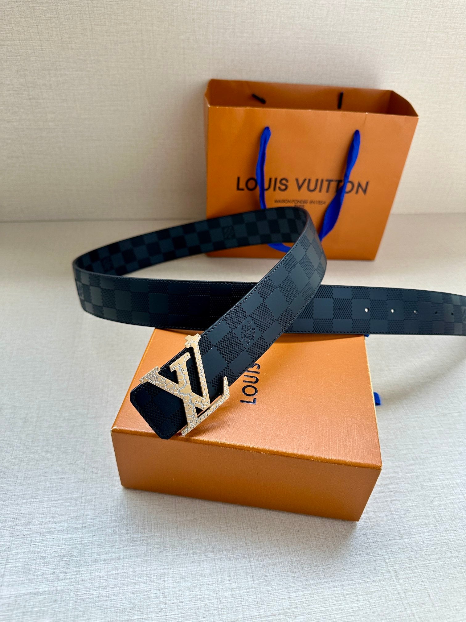 Louis Vuitton belt laid flat, dark blue checkered strap with silver-tone LV buckle