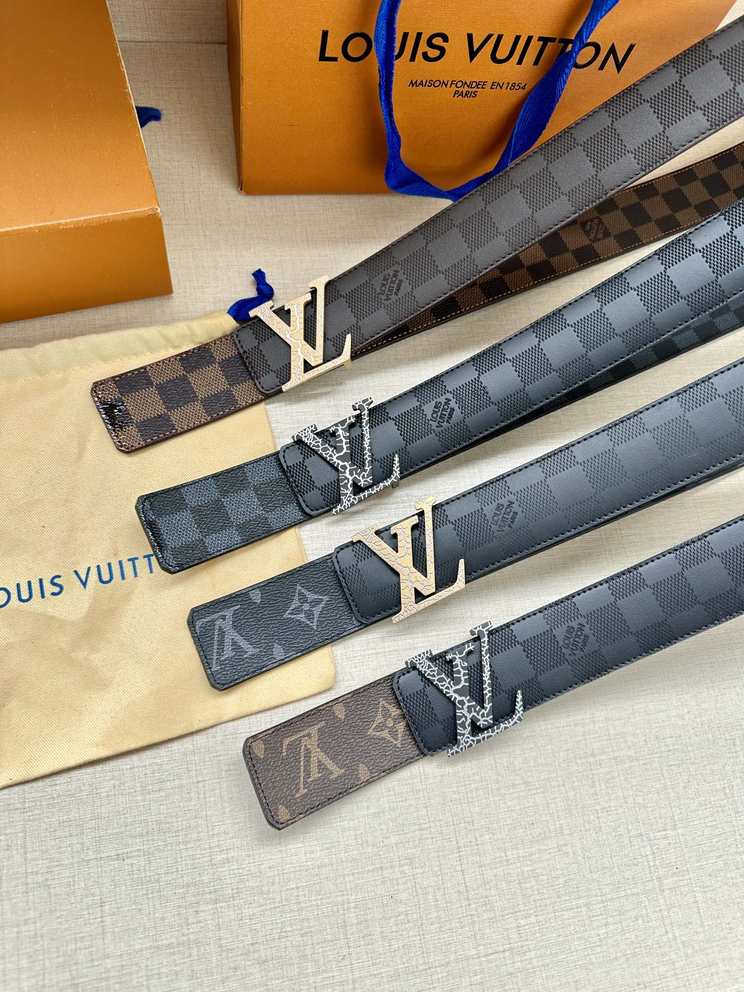 Louis Vuitton belts with dark checker straps and LV buckles, multiple end tabs