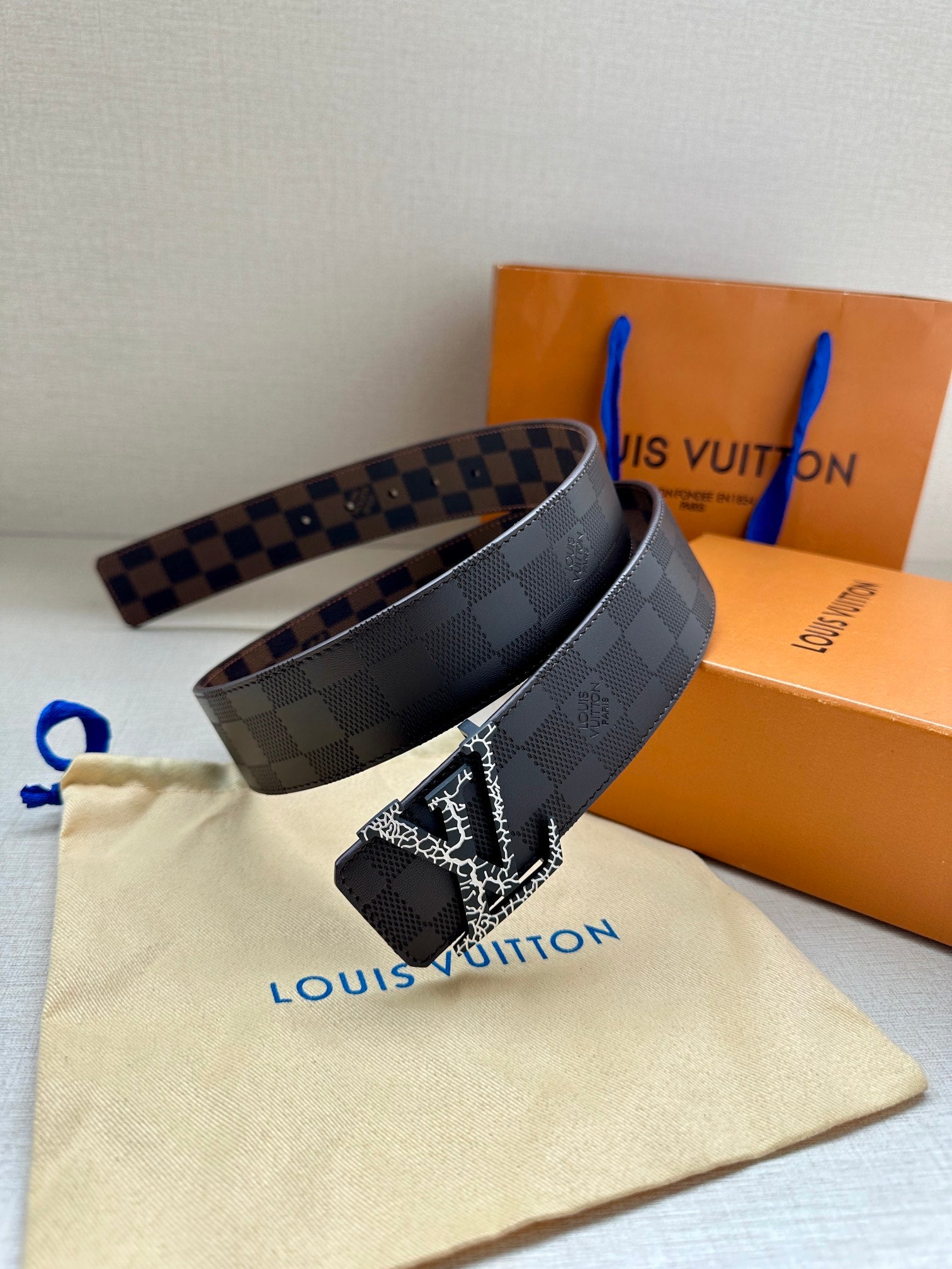 Louis Vuitton belt with dark checker strap and metallic LV buckle, side view