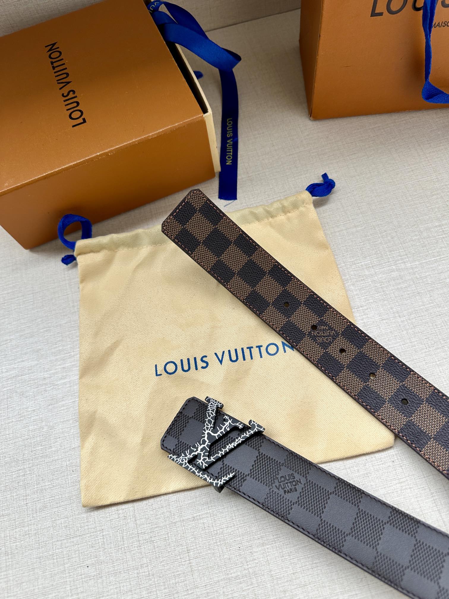 Louis Vuitton belt strap with dark checker pattern and metallic LV buckle detail