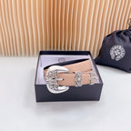 Leather belt with tan strap and ornate silver-tone buckle, navy lining visible