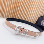 Leather belt with navy edge and ornate silver-tone buckle, tan strap with eyelets