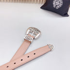 Tan belt strap close-up with ornate silver buckle and metal pin adjustment holes