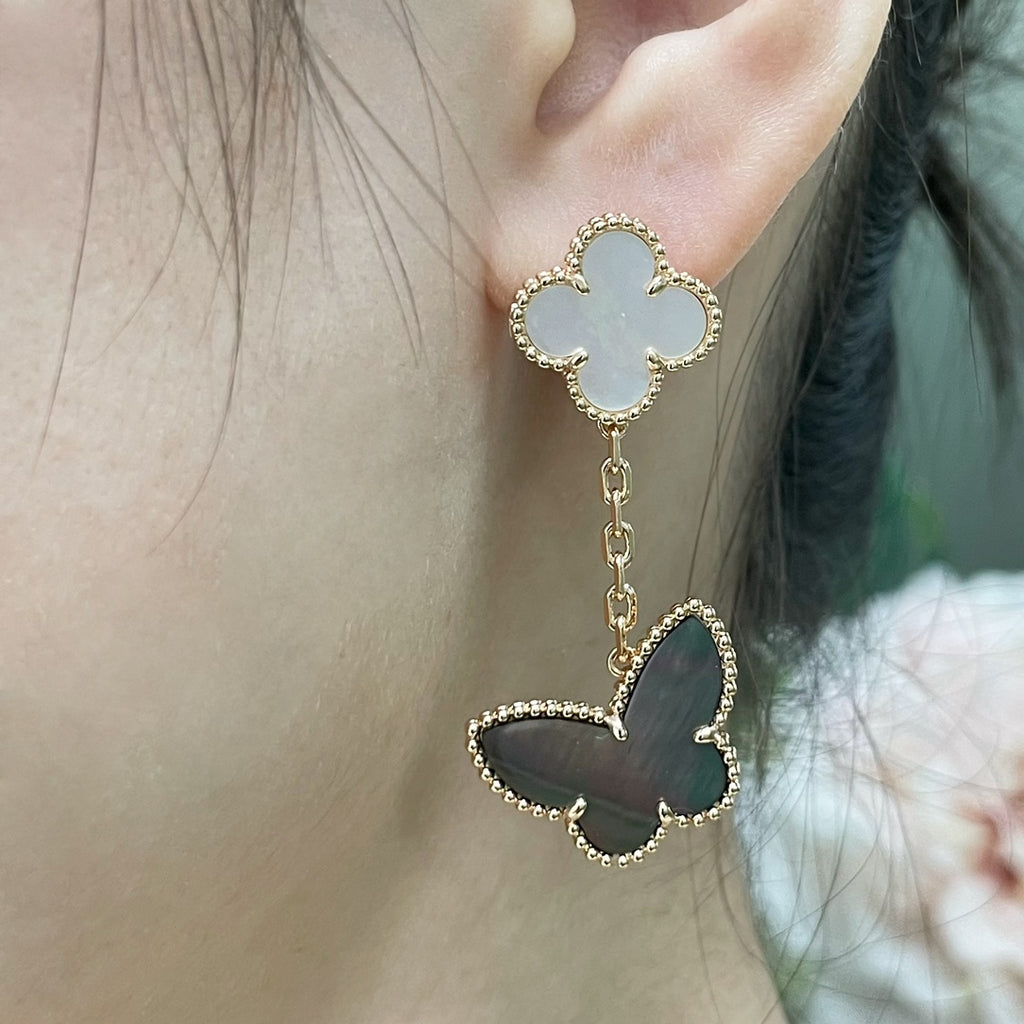 Butterfly dangle earrings with white clover stud and gold-tone chain, on-ear view