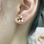 Gold-tone floral stud earring with ruby red center stone on ear