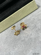 Gold-tone floral stud earrings with ruby red center stones, close-up