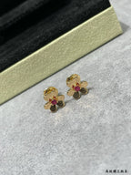 Gold-tone floral stud earrings with ruby red center stones on jewelry stand