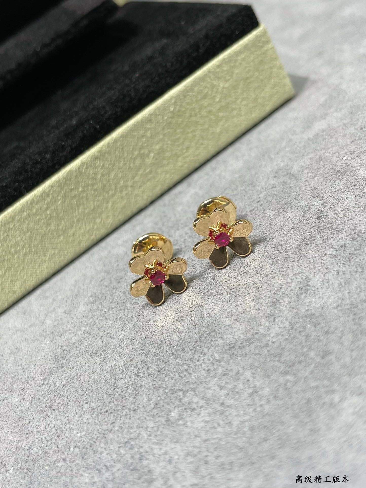 Gold-tone floral stud earrings with ruby red center stones, pair view