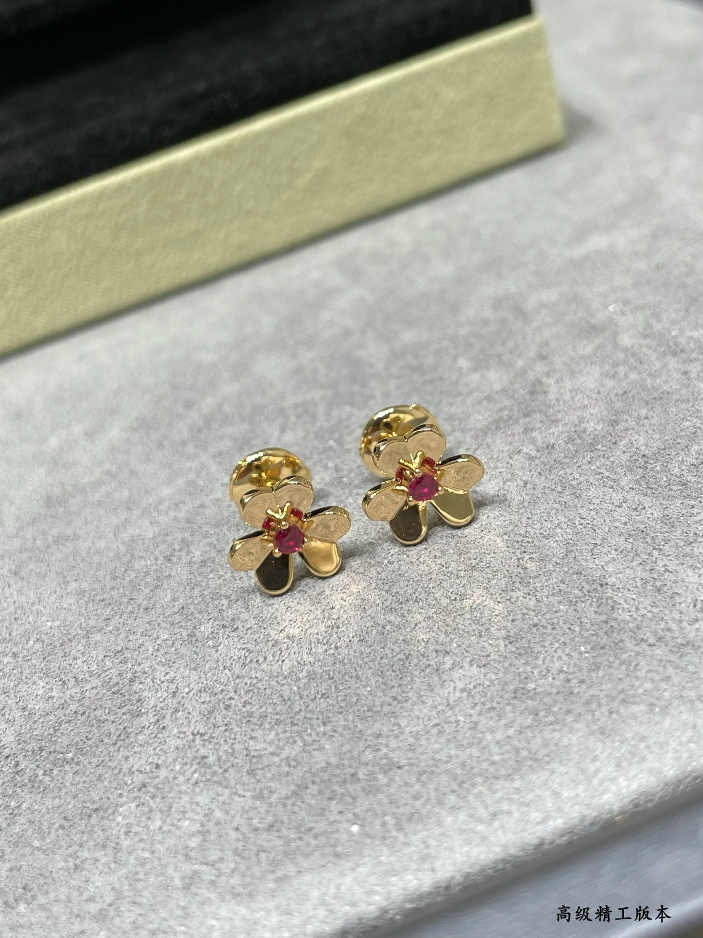 Gold-tone floral stud earrings with ruby red center stones, pair on felt