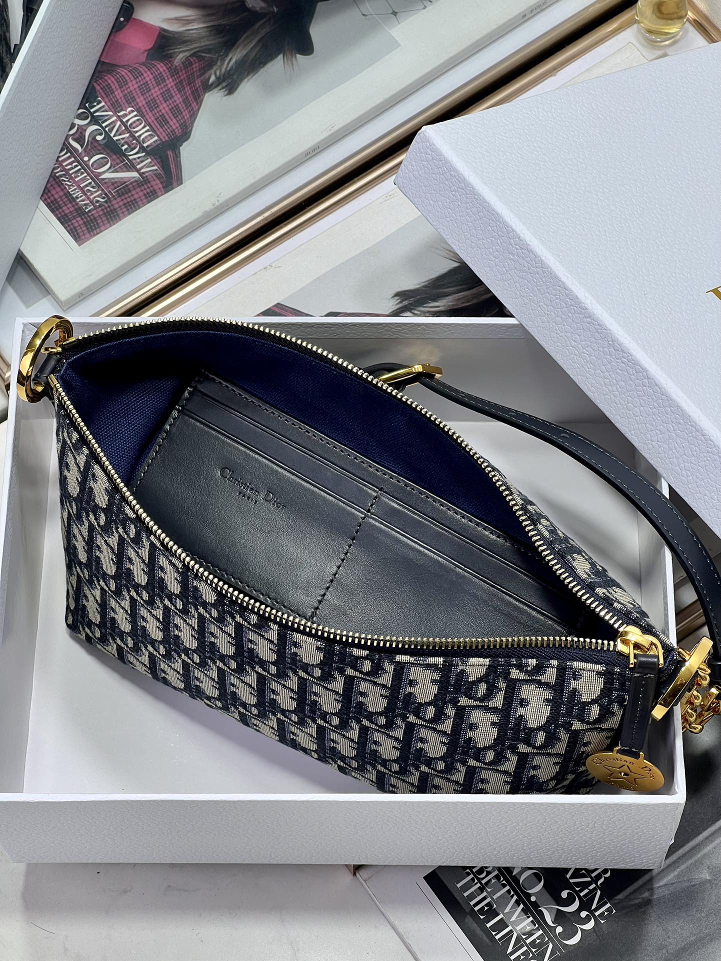 Dior crossbody bag with blue Dior logo pattern, zip top, and interior pocket detail