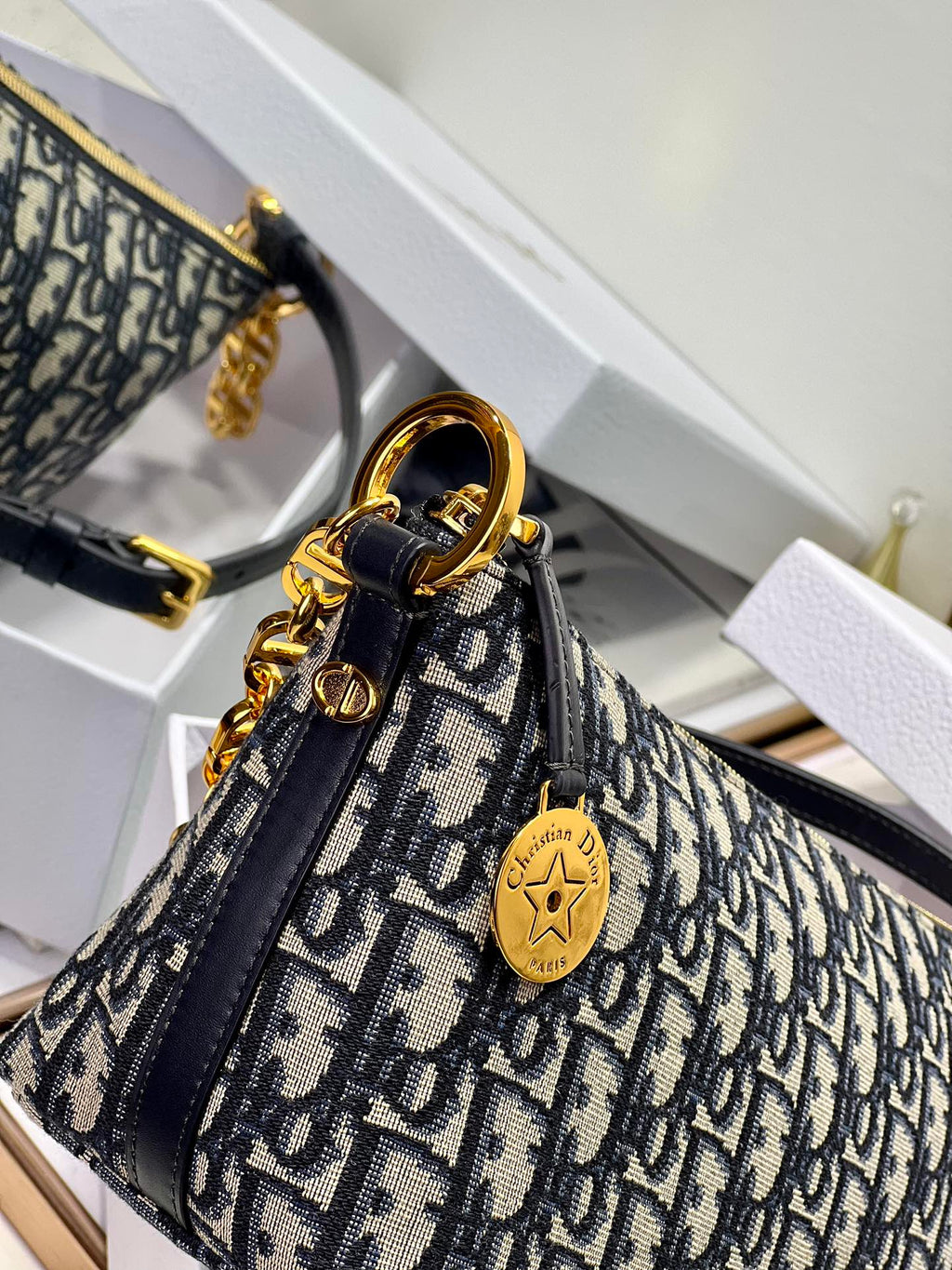 Dior monogram mini shoulder bag close-up with gold emblem charm and chain strap