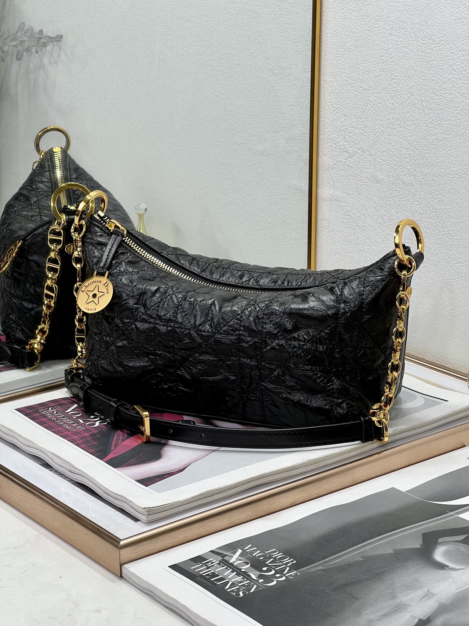 Dior black hobo bag with gold chain shoulder strap and zipper closure.