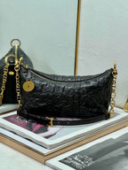 Dior black hobo bag with gold chain strap, zip-top, round logo charm.