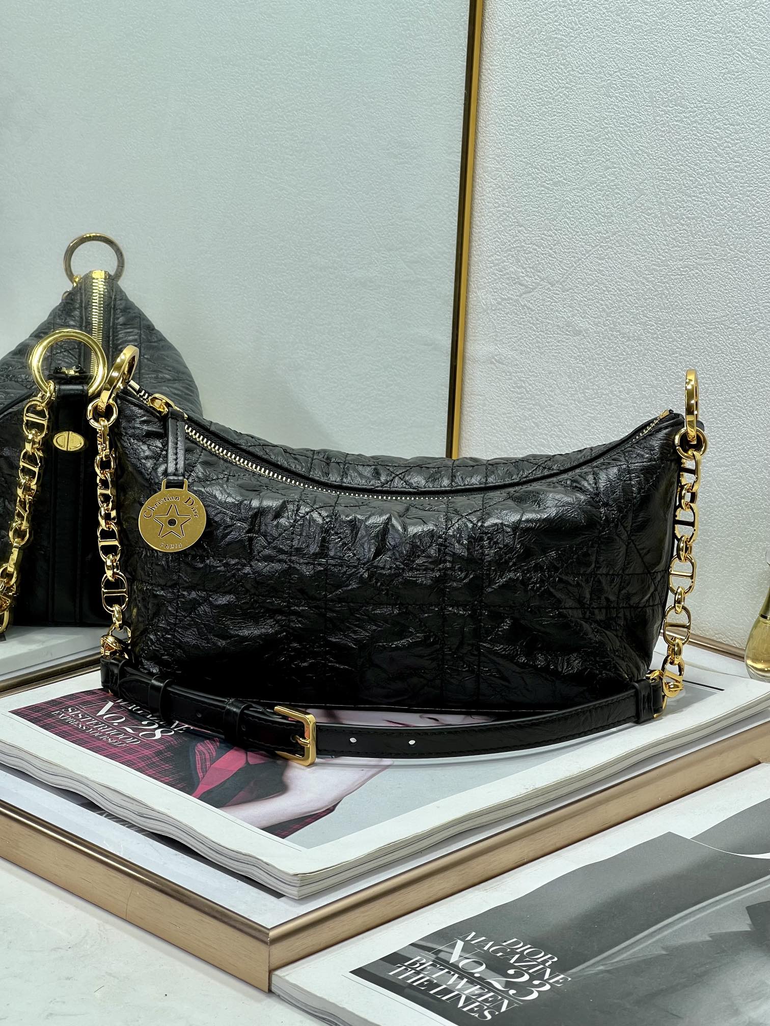Dior black hobo bag with gold chain strap, zip-top, round logo charm.